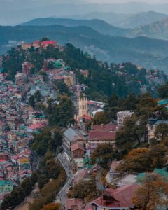 A stunning aerial view of Shimla, showcasing colorful hillside architecture amidst lush greenery.
